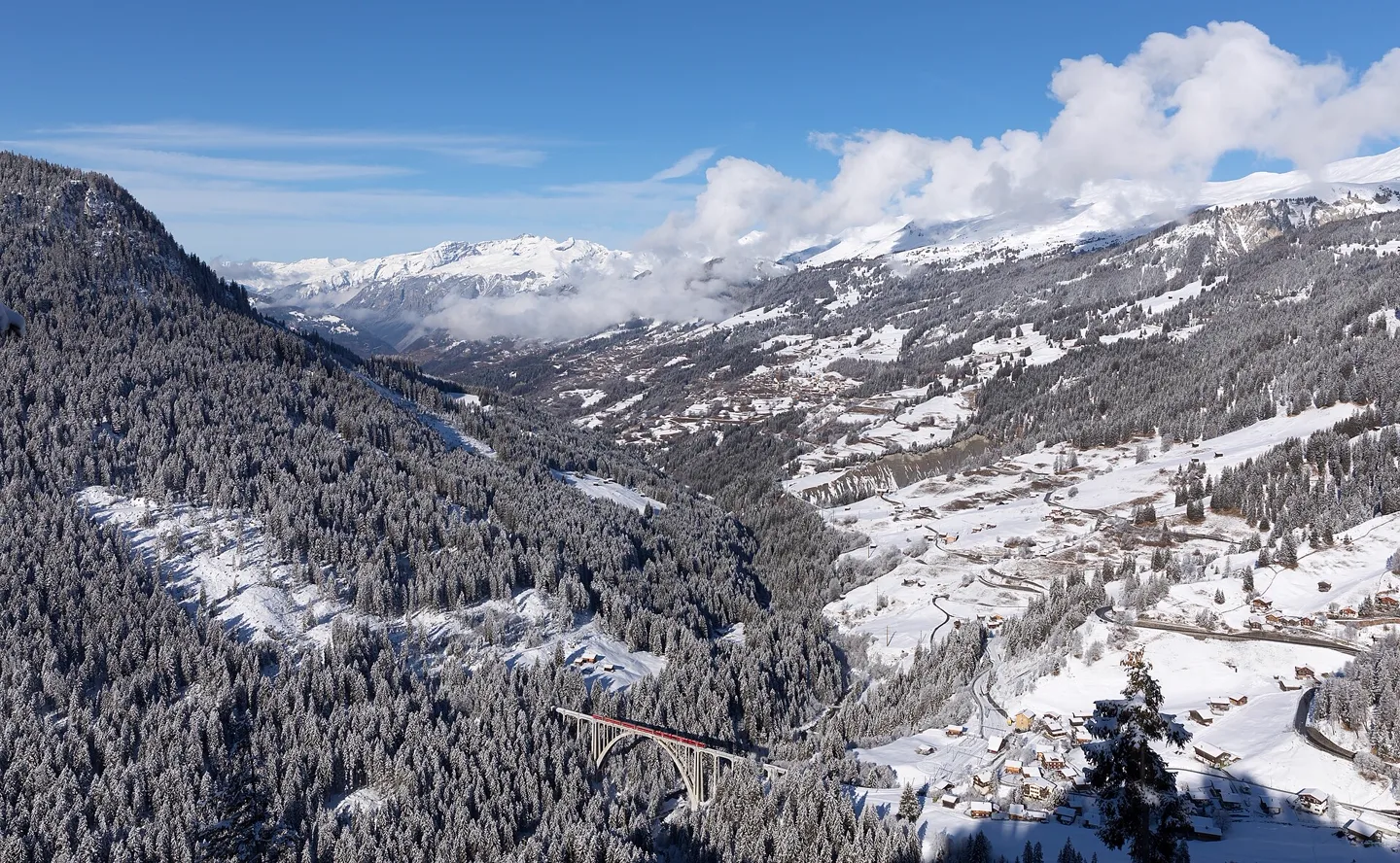 Een rode Zwitserse trein op het Langwieser viaduct in de Alpen