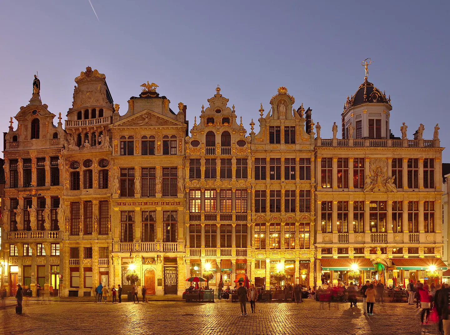 De verlichte gildehuizen met goudkleurige gevels aan de Grote Markt van Brussel in de schemering
